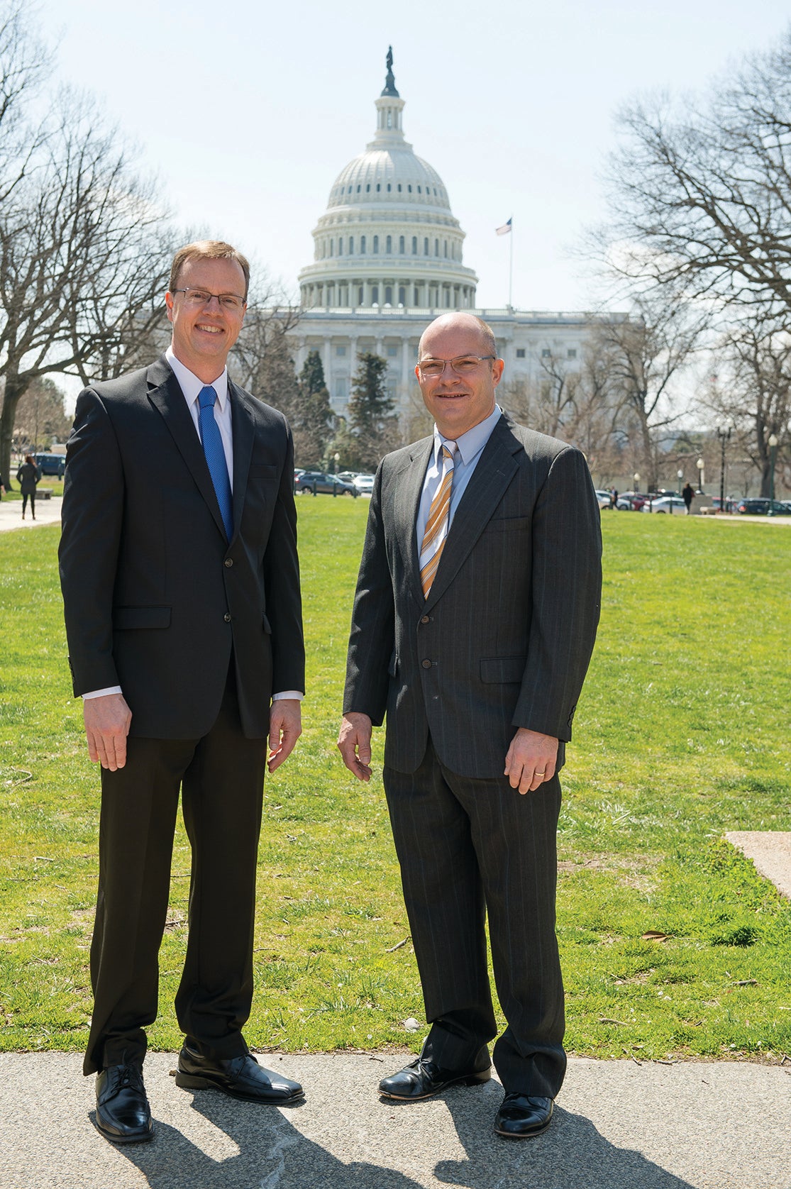 two men stand in front of capital building in Washington, DC