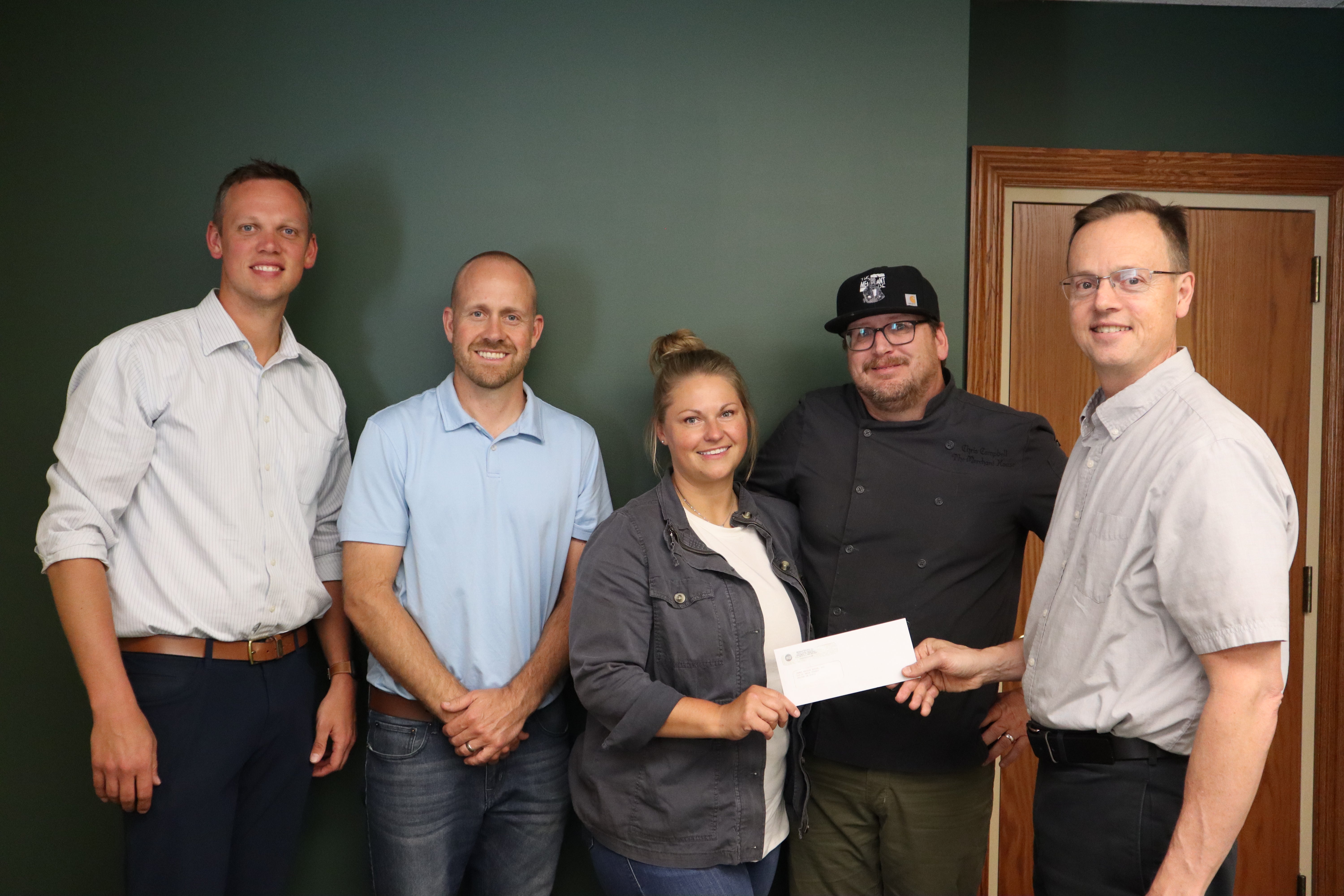 Michael Hoying, Phil Moeller, Cassie Campbell, and Chris Campbell accept a loan from Midwest Electric CEO Matt Berry to open a new restaurant, The James Watson House, in downtown Celina in 2023.