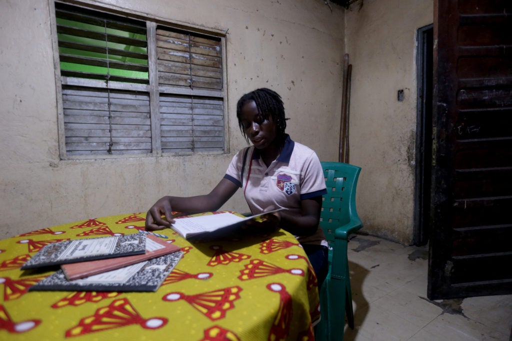 Citizen studying by light at her home in Totota, Liberia. From NRECA Internationl.